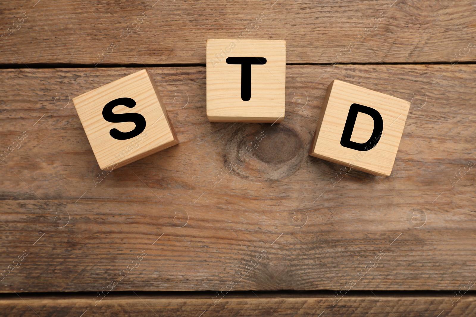 Photo of Abbreviation STD made with cubes on wooden table, flat lay