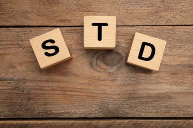 Photo of Abbreviation STD made with cubes on wooden table, flat lay