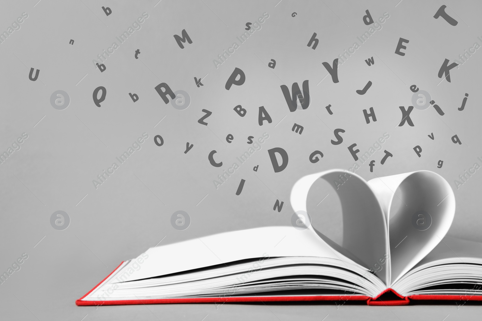 Image of Letters flying out from open book on grey background, closeup