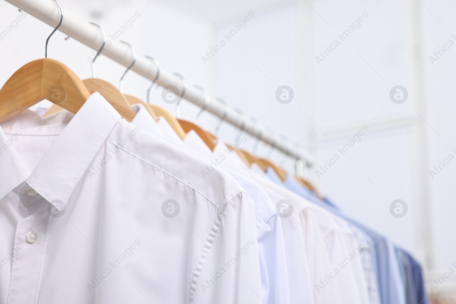 Photo of Dry-cleaning service. Many different clothes hanging on rack indoors, closeup