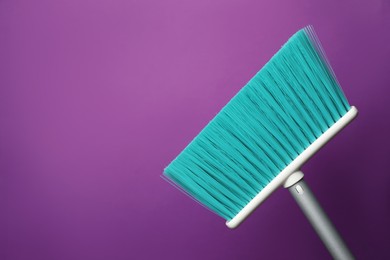 Photo of Plastic broom on purple background. Space for text
