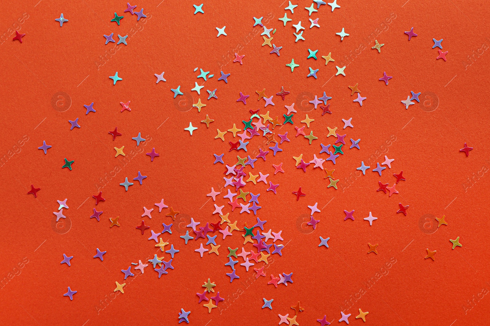 Photo of Shiny bright colorful glitter on orange background, top view