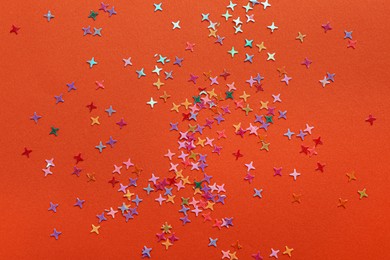 Photo of Shiny bright colorful glitter on orange background, top view