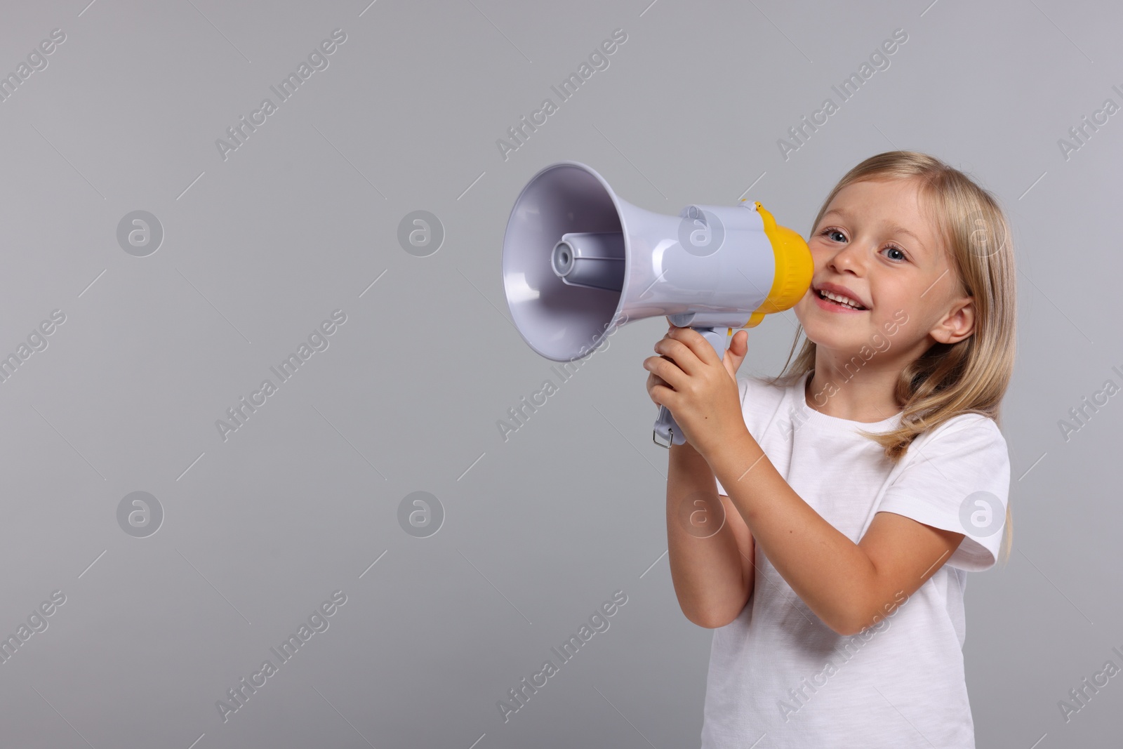 Photo of Special promotion. Little girl with megaphone on grey background. Space for text