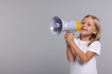 Photo of Special promotion. Little girl with megaphone on grey background. Space for text