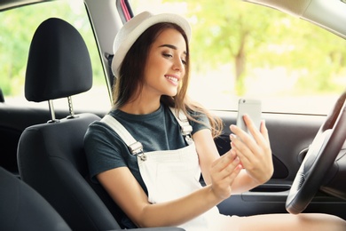 Photo of Happy young woman taking selfie in car