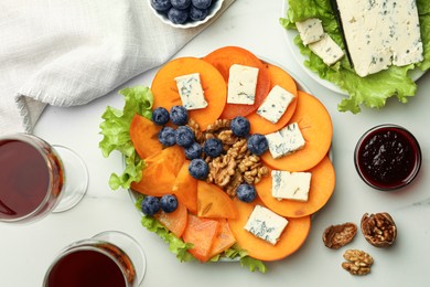 Delicious persimmon with blue cheese on white marble table, flat lay