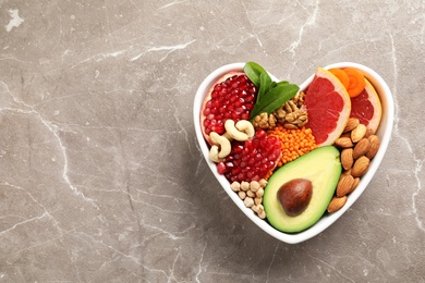 Bowl with heart-healthy diet products on color background, top view. Space for text