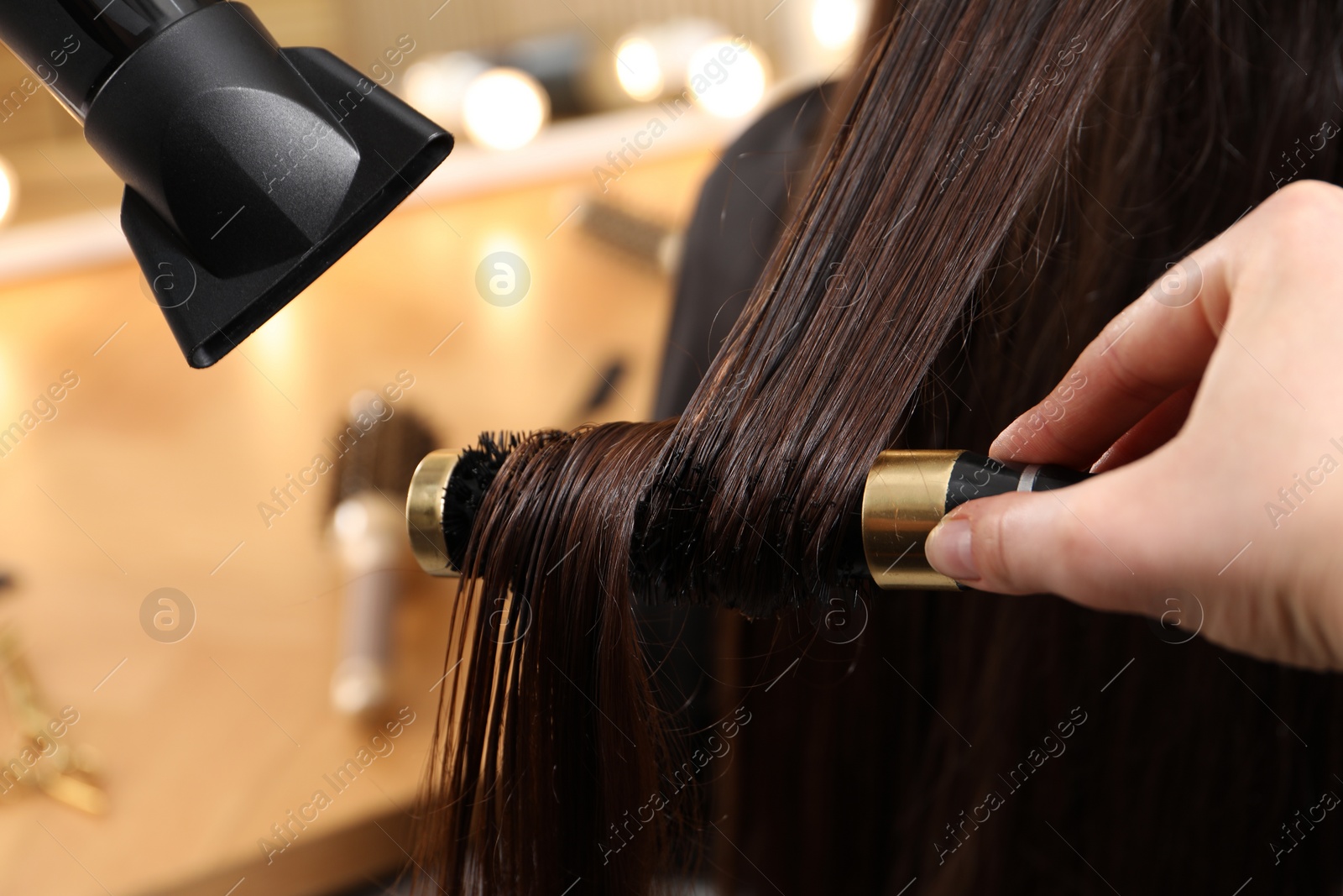 Photo of Hairdresser blow drying client's hair in salon, closeup