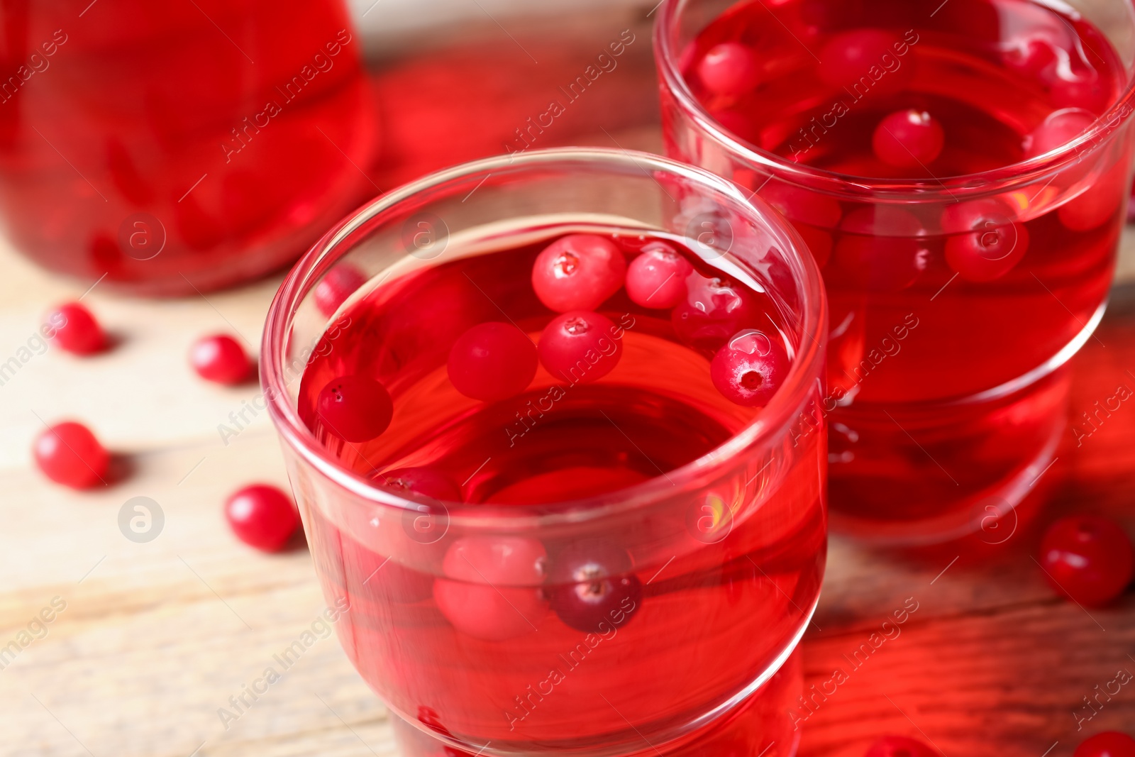 Photo of Tasty cranberry juice in glasses and fresh berries on wooden table, closeup