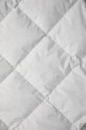 Soft quilted blanket as background, top view