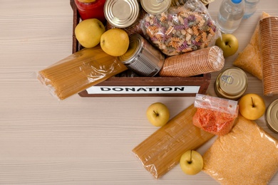 Photo of Donation box and different products on wooden table, top view