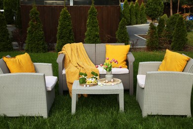 Photo of Easter decorations. Bouquet of tulips in vase, bunny figures and decorated eggs on table in backyard