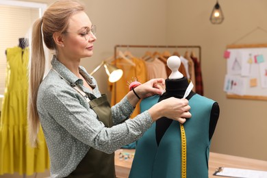 Photo of Dressmaker with measuring tape working in atelier