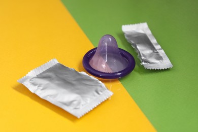 Torn package with condom on color background. Safe sex