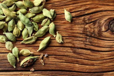 Pile of dry cardamom pods on wooden table, top view. Space for text