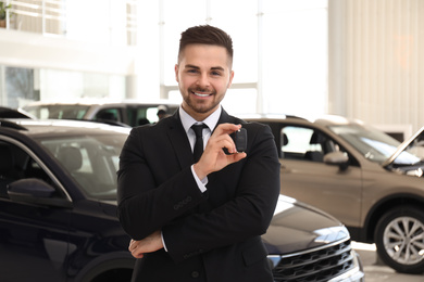 Photo of Salesman with key in modern car salon