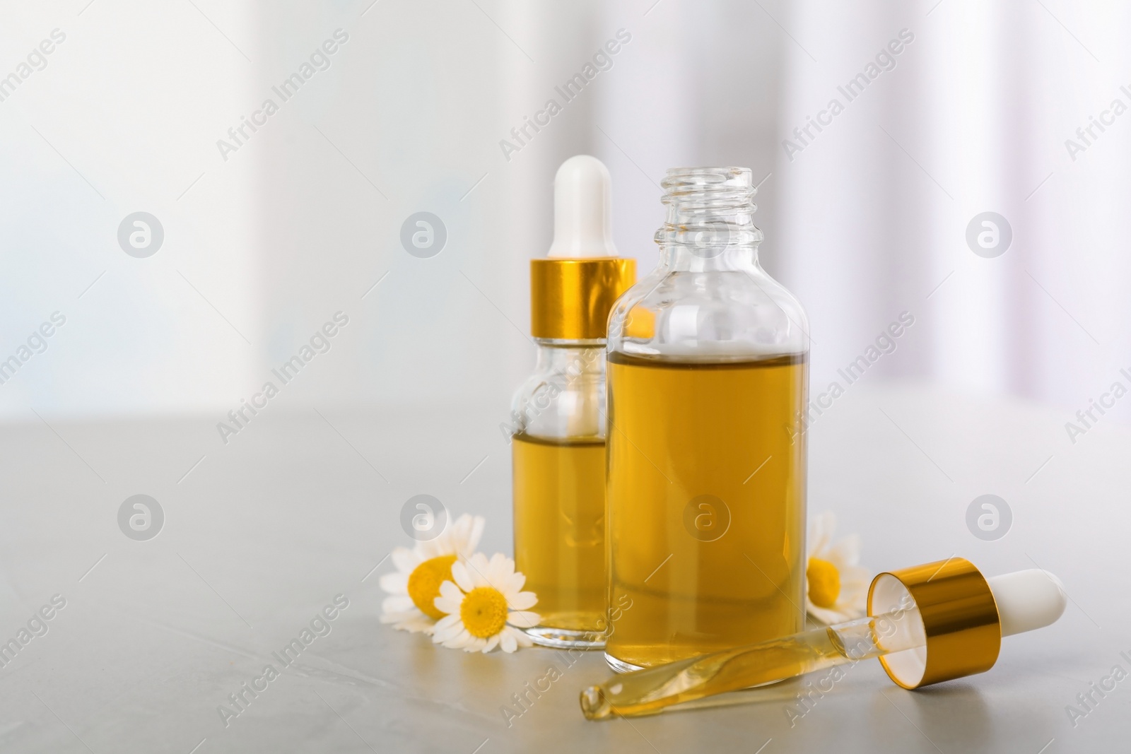 Photo of Composition with bottles of chamomile essential oil on table. Space for text