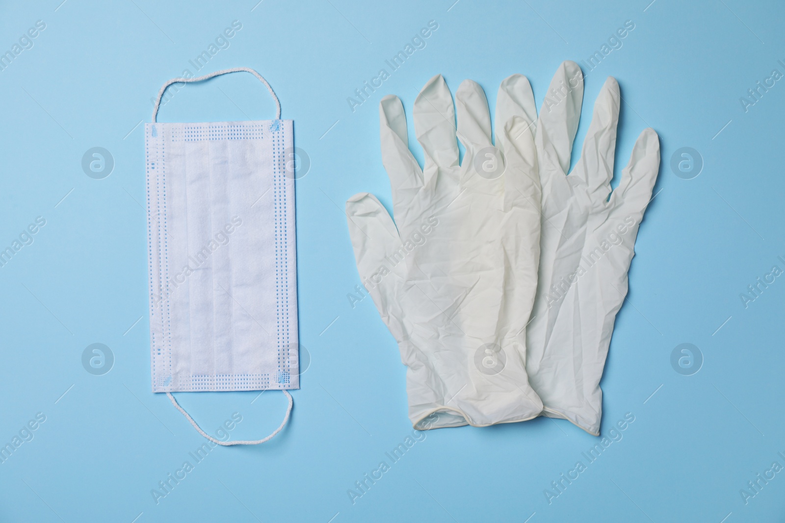 Photo of Medical gloves and protective mask on light blue background, flat lay. Safety equipment