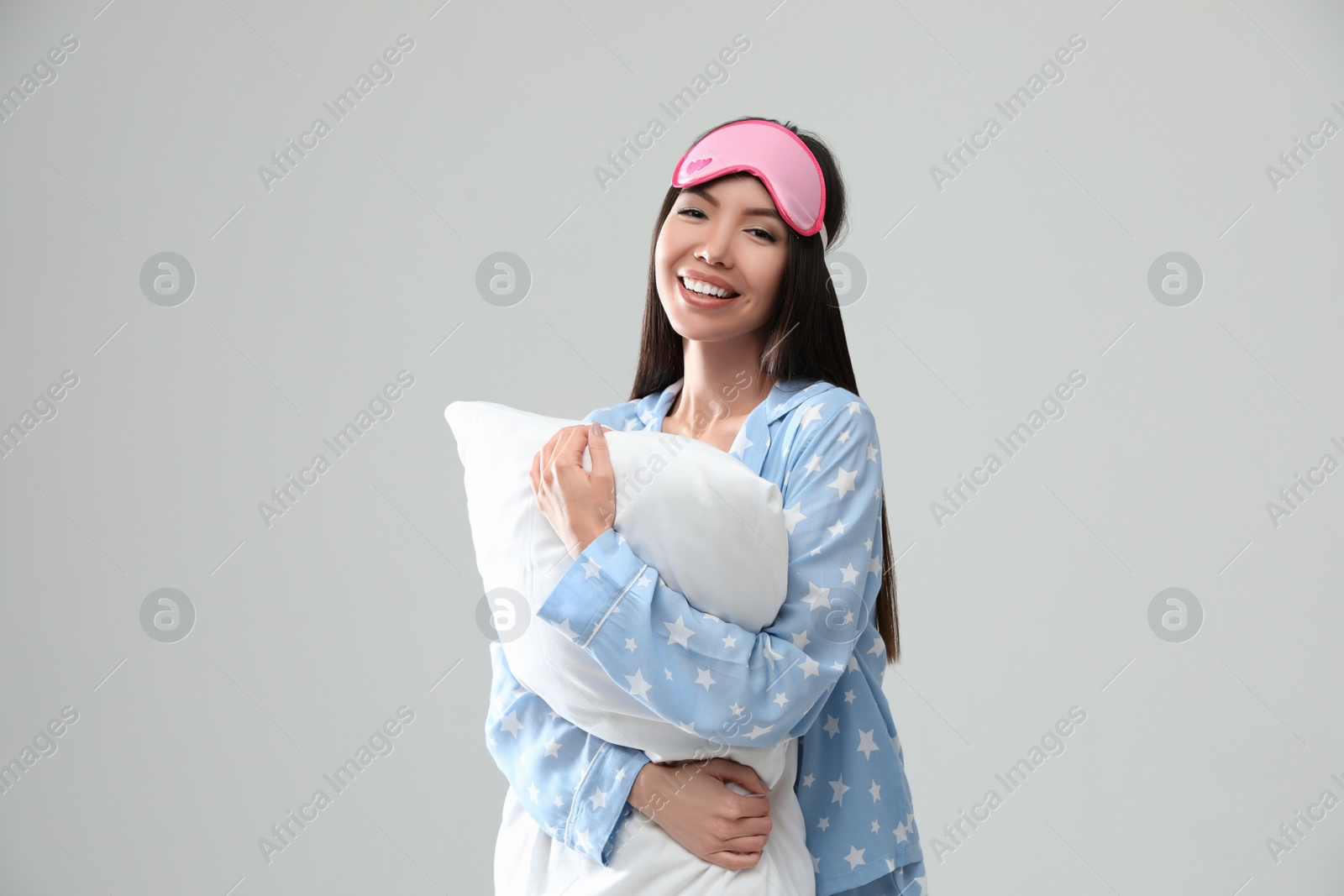 Photo of Beautiful Asian woman with pillow on light grey background. Bedtime