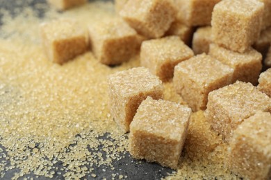 Photo of Brown sugar cubes on grey table, closeup