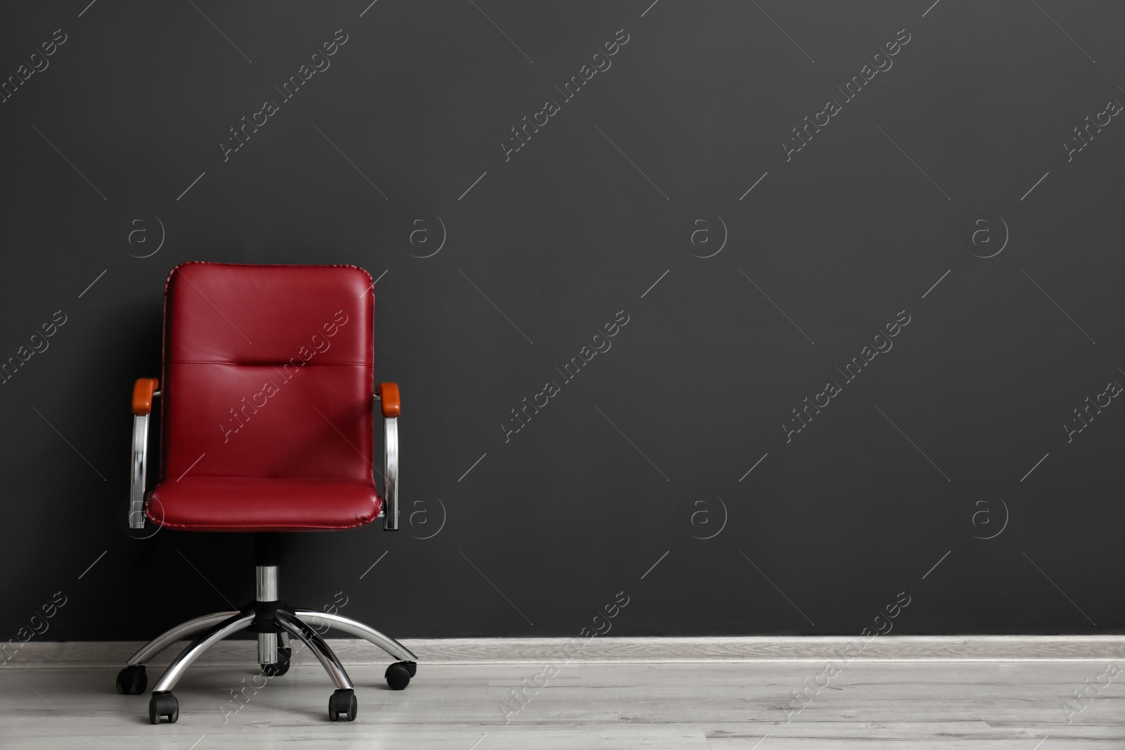 Photo of Comfortable office chair near black wall indoors. Space for text