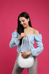 Fashionable young woman with stylish bag on pink background