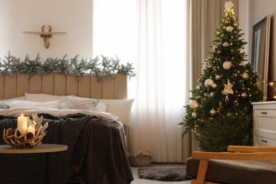 Photo of Beautiful decorated Christmas tree with fairy lights in bedroom interior