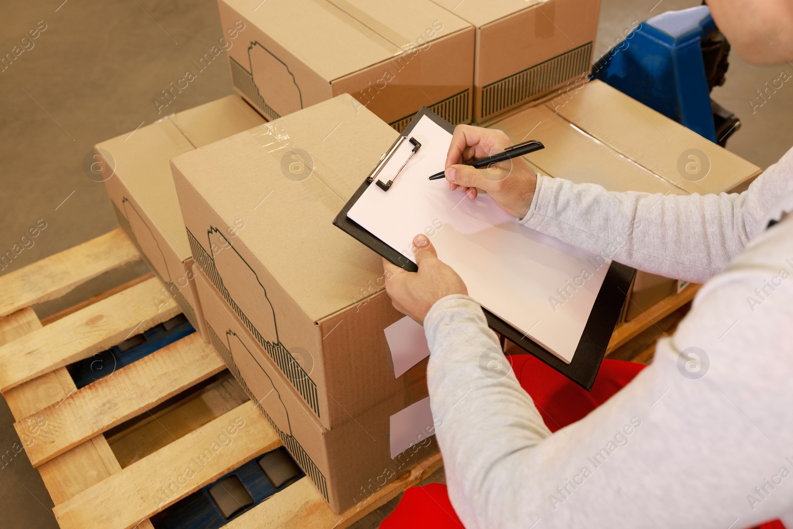 Image of Worker holding clipboard near pallet with boxes, closeup