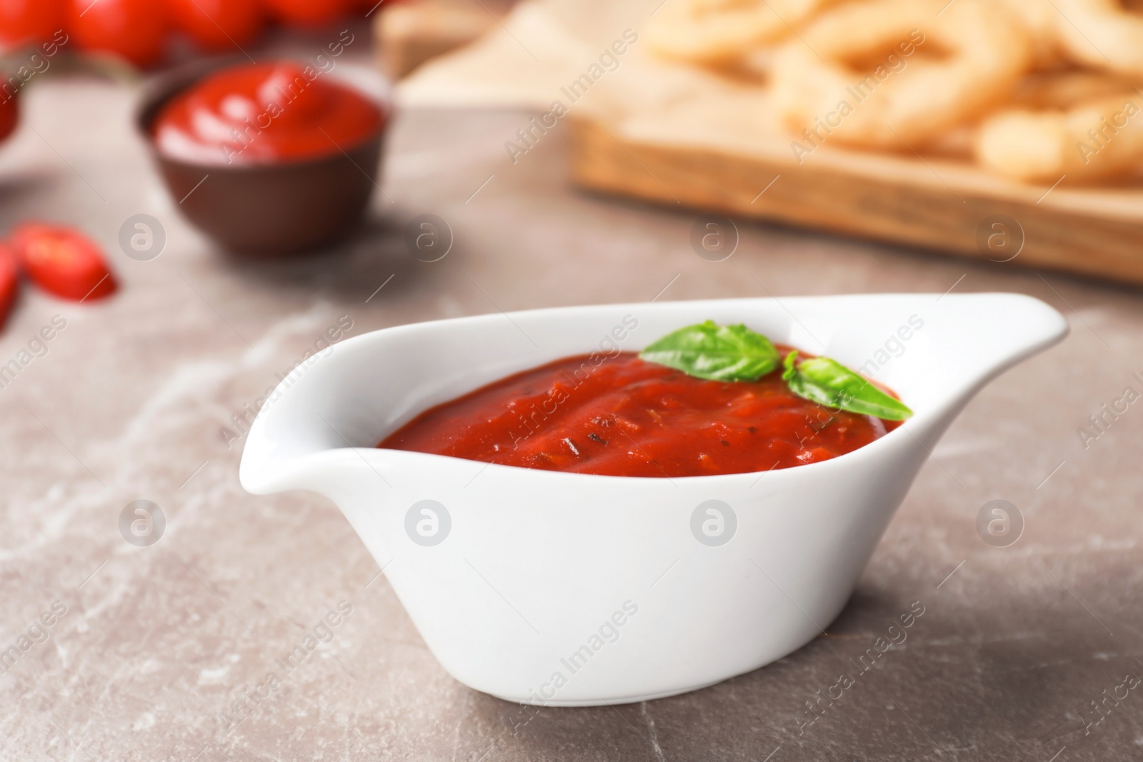 Photo of Gravy boat with spicy chili sauce on dark table