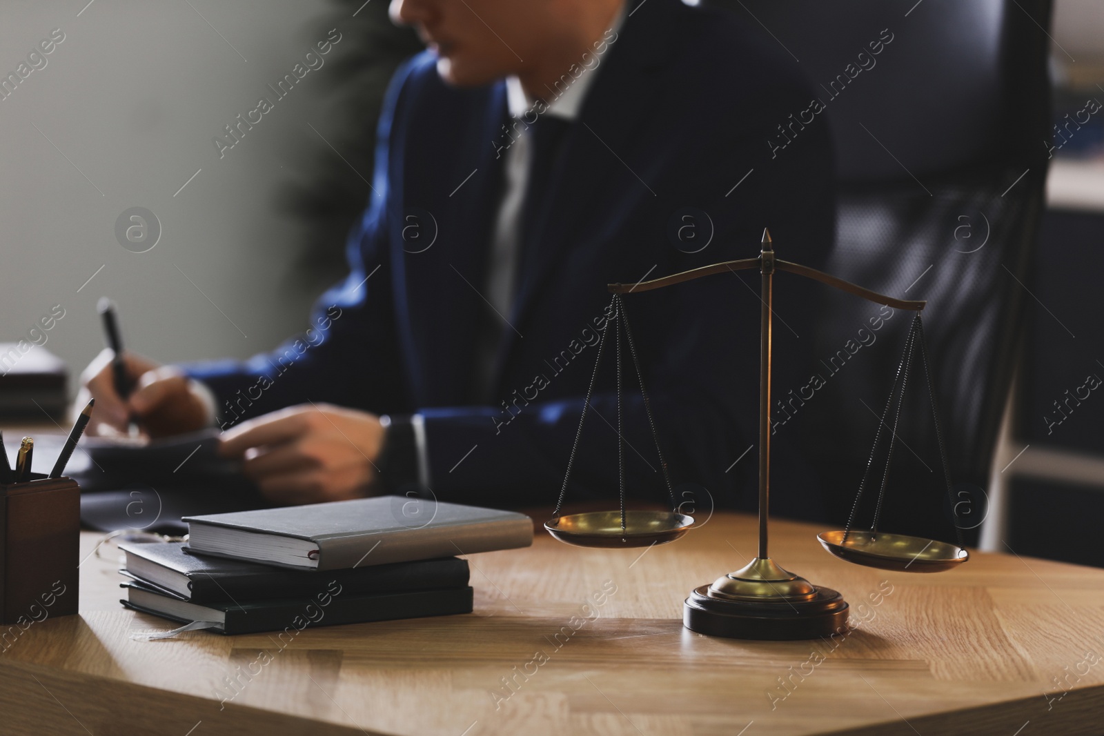 Photo of Male lawyer working at table in office, focus on scales of justice