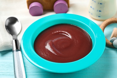 Photo of Bowl of healthy baby food on light blue wooden table, closeup