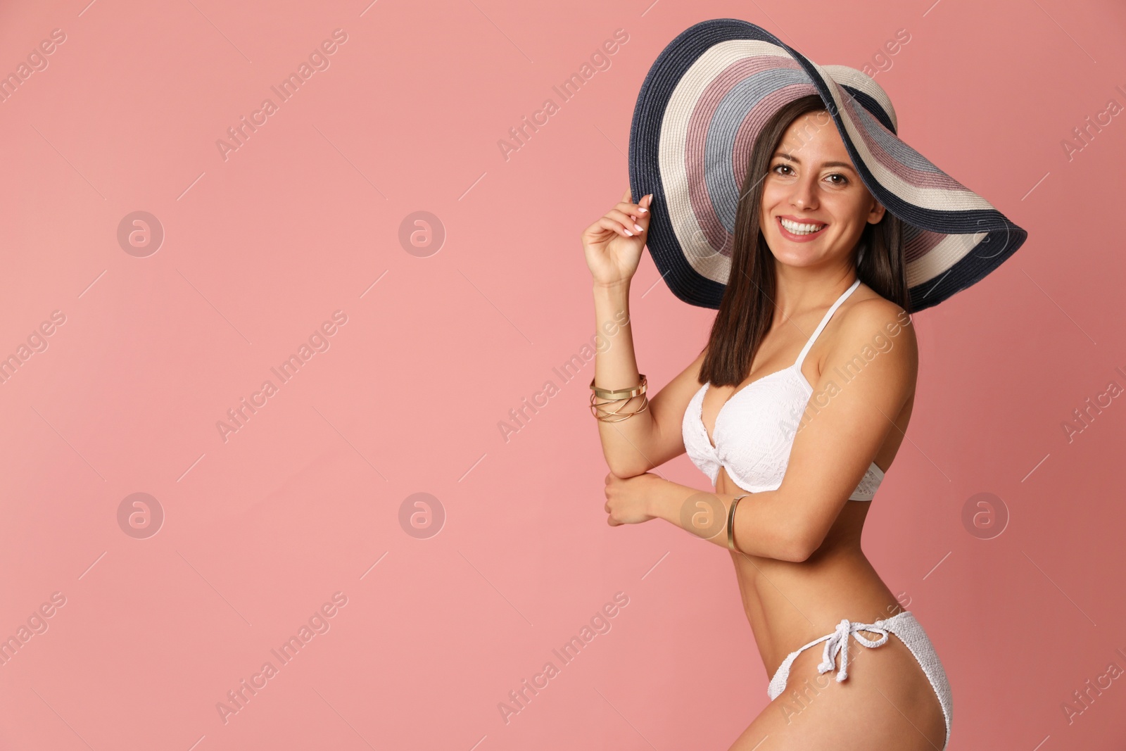 Photo of Pretty sexy woman with slim body in stylish  white bikini on coral background, space for text