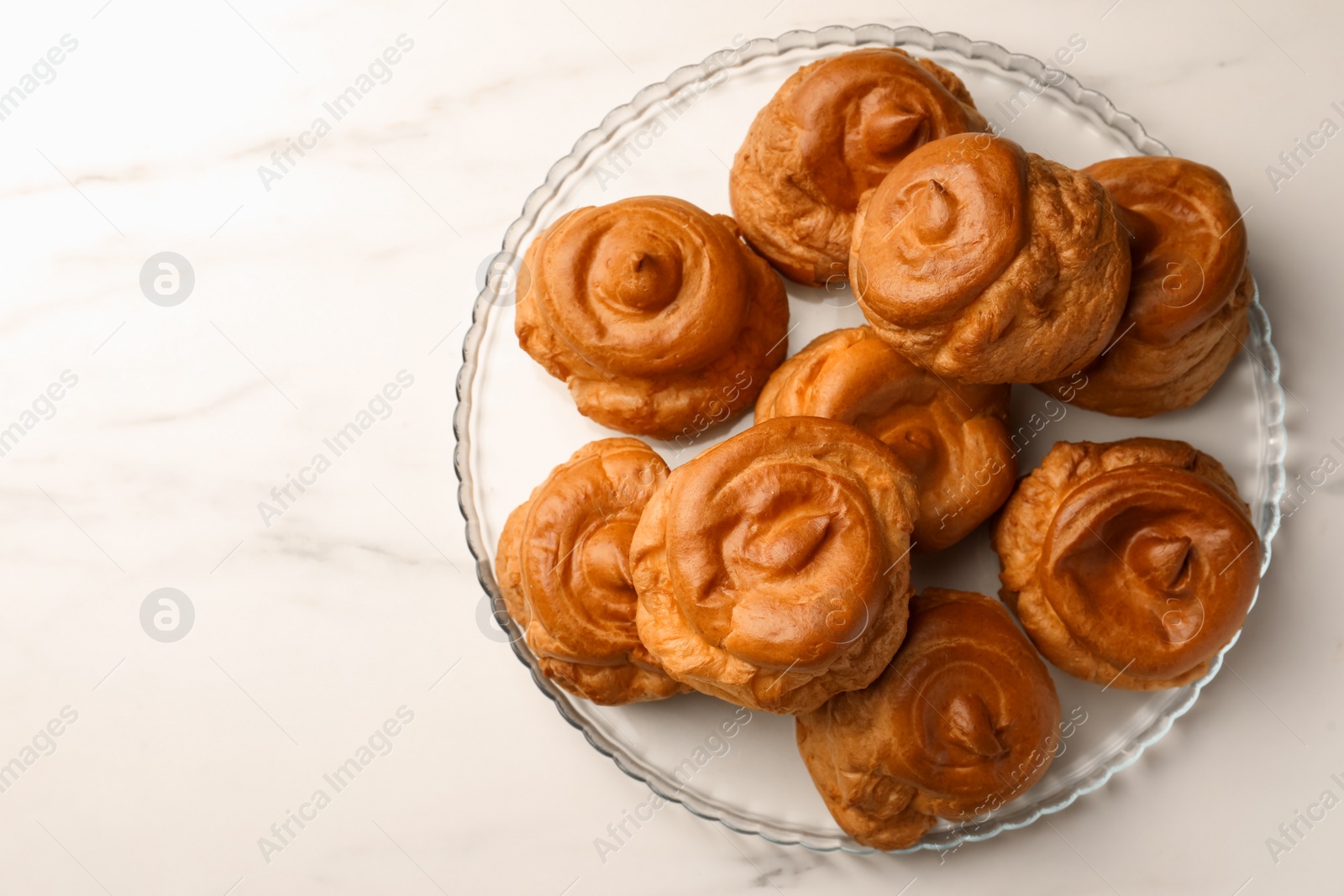 Photo of Delicious profiteroles on white marble table, top view. Space for text