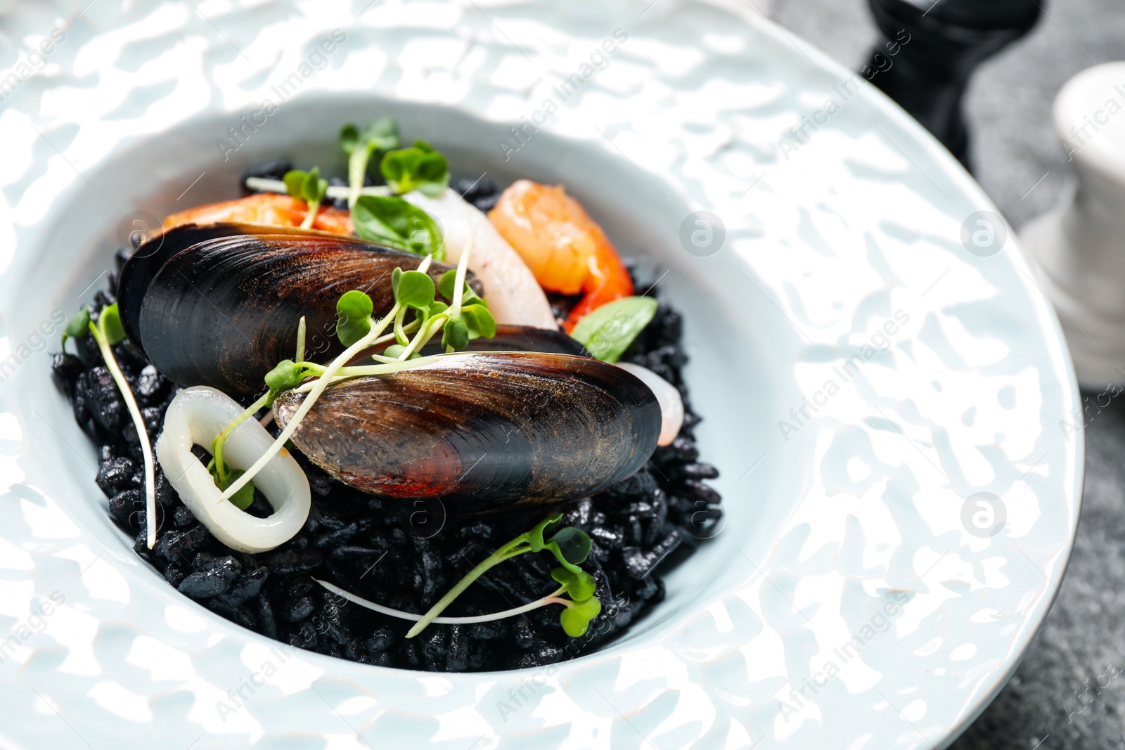 Photo of Delicious black risotto with seafood in plate, closeup