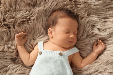 Cute newborn baby sleeping on fluffy blanket, top view