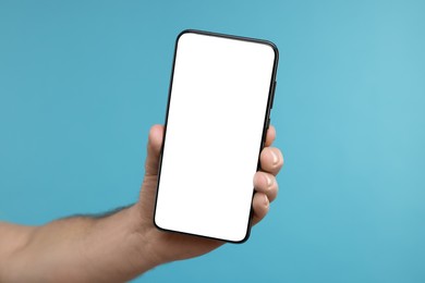 Photo of Man showing smartphone on light blue background, closeup. Mockup for design