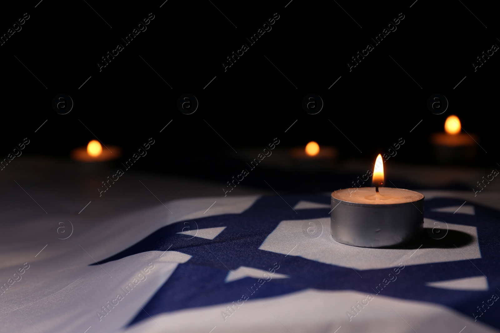 Photo of Burning candle on flag of Israel. Holocaust memory day