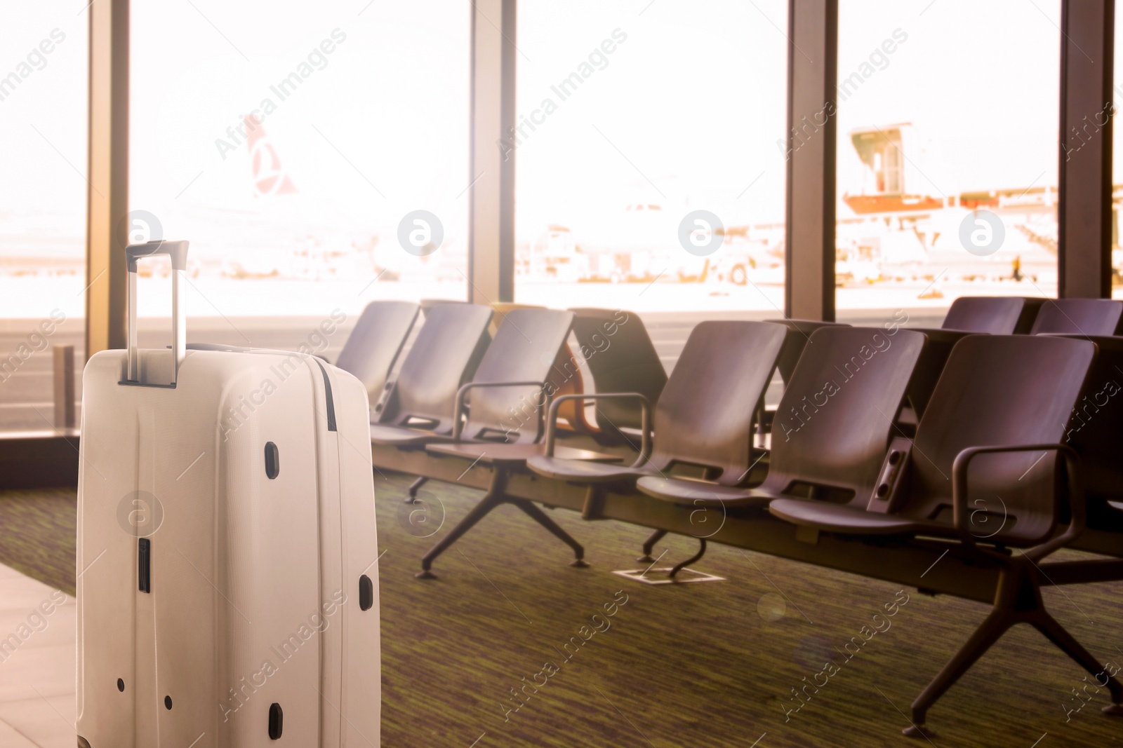 Image of Stylish white suitcase near waiting seats in airport terminal