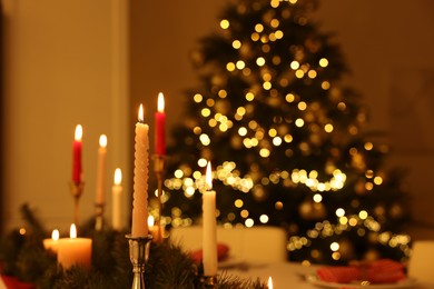 Burning candles and Christmas tree in room, space for text