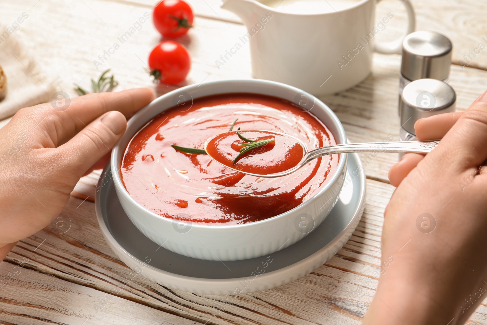 Photo of Woman eating fresh homemade tomato soup at wooden table, closeup