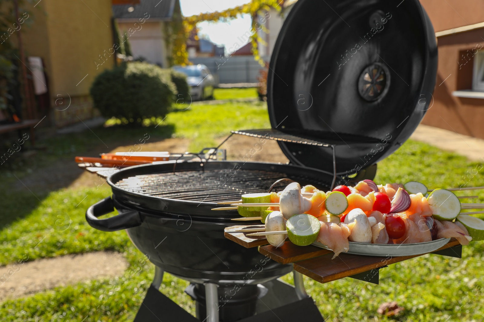 Photo of Skewers with meat and vegetables near barbecue grill outdoors