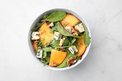 Tasty salad with persimmon, blue cheese and walnuts served on white marble table, top view