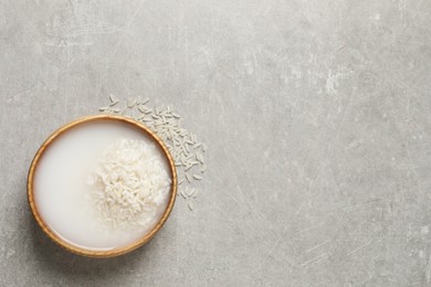 Rice soaked in water on light grey table, top view. Space for text