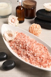 Photo of Natural sea salt in bowl, spa stones, roses and rattan ball on wooden table