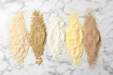 Photo of Stripes of different flour types on marble background, top view