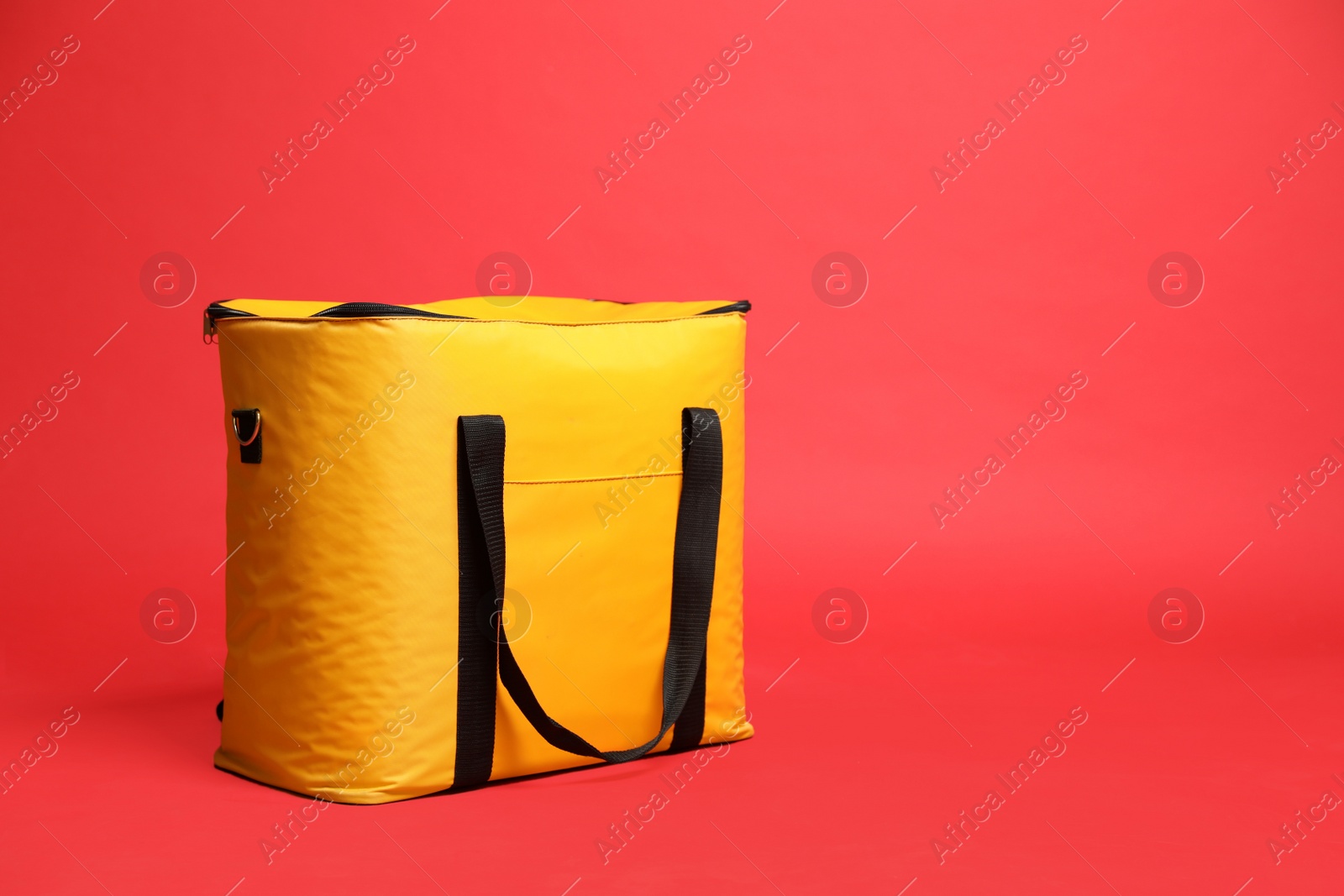 Photo of Modern yellow thermo bag on red background. Space for text