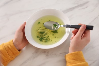Photo of Woman eating tasty soup at white marble table, closeup