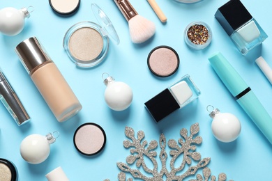 Flat lay composition with makeup products and Christmas decor on color background