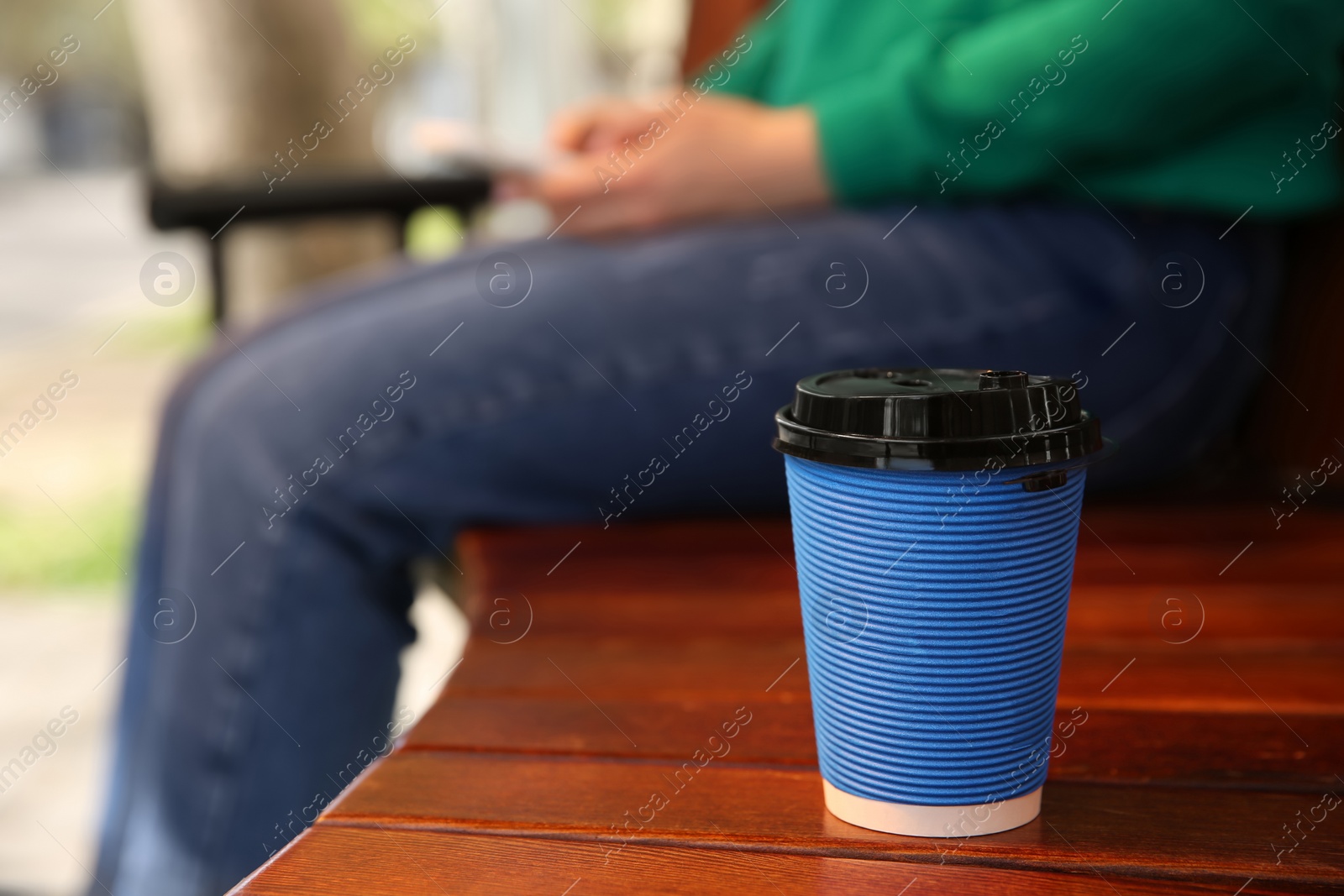 Photo of Takeaway coffee cup and woman on bench outdoors